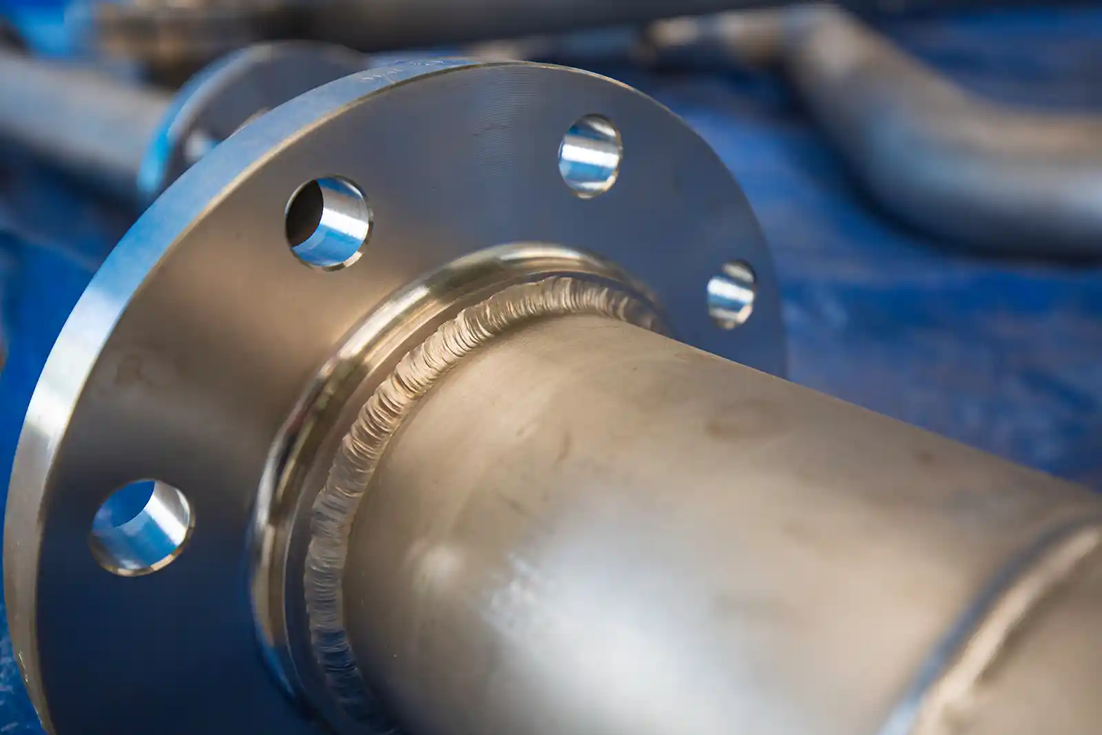 A pipe with a flange made of tungsten on a blue background.
